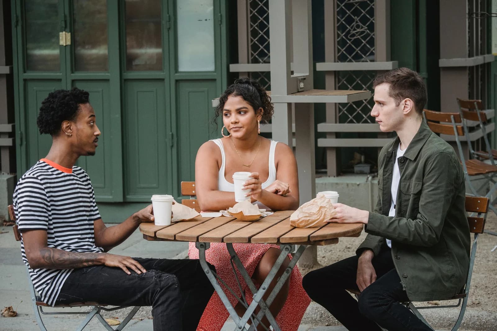 Three friends talking over coffee at an outdoor table
